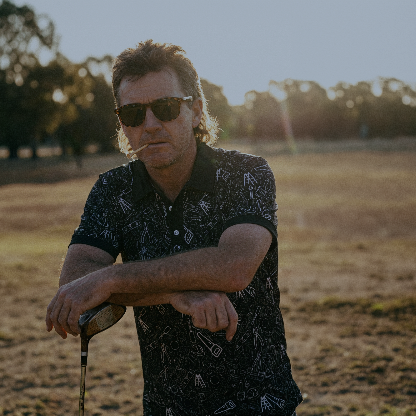 Man wearing sunglasses and a patterned shirt in an outdoor setting